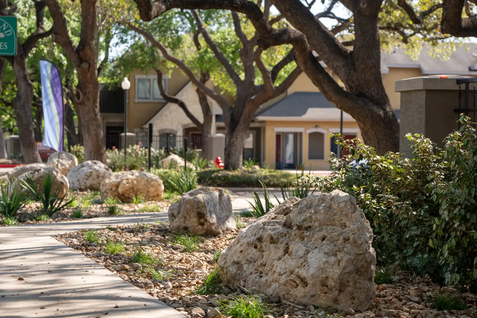 Boulders and layered planting along the shaded community walkway.